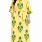 Woman wearing a yellow and green patterned dress on a white background