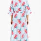 Woman wearing a long, patterned dress with a white background
