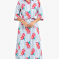 Woman wearing a long dress with a colorful fruit pattern on a white background