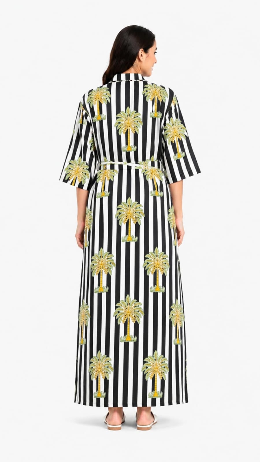 Woman wearing a black and white striped dress with palm tree patterns on a white background
